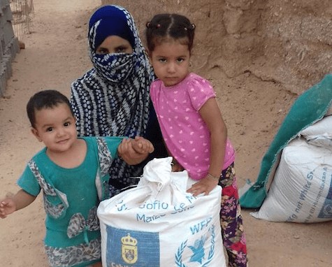 Una madre y su dos hijos, junto a uno de los sacos de gofios enviados a Tinduf desde Gran Canaria (Foto TA)